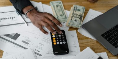 Overhead view of financial documents with calculator, cash, and laptop for financial planning.